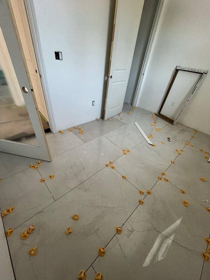 Tile flooring installation in progress with spacing clips and layout preparation