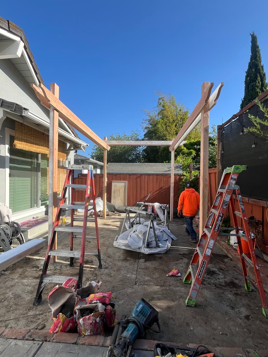 Outdoor construction crew installing pergola structure on residential property